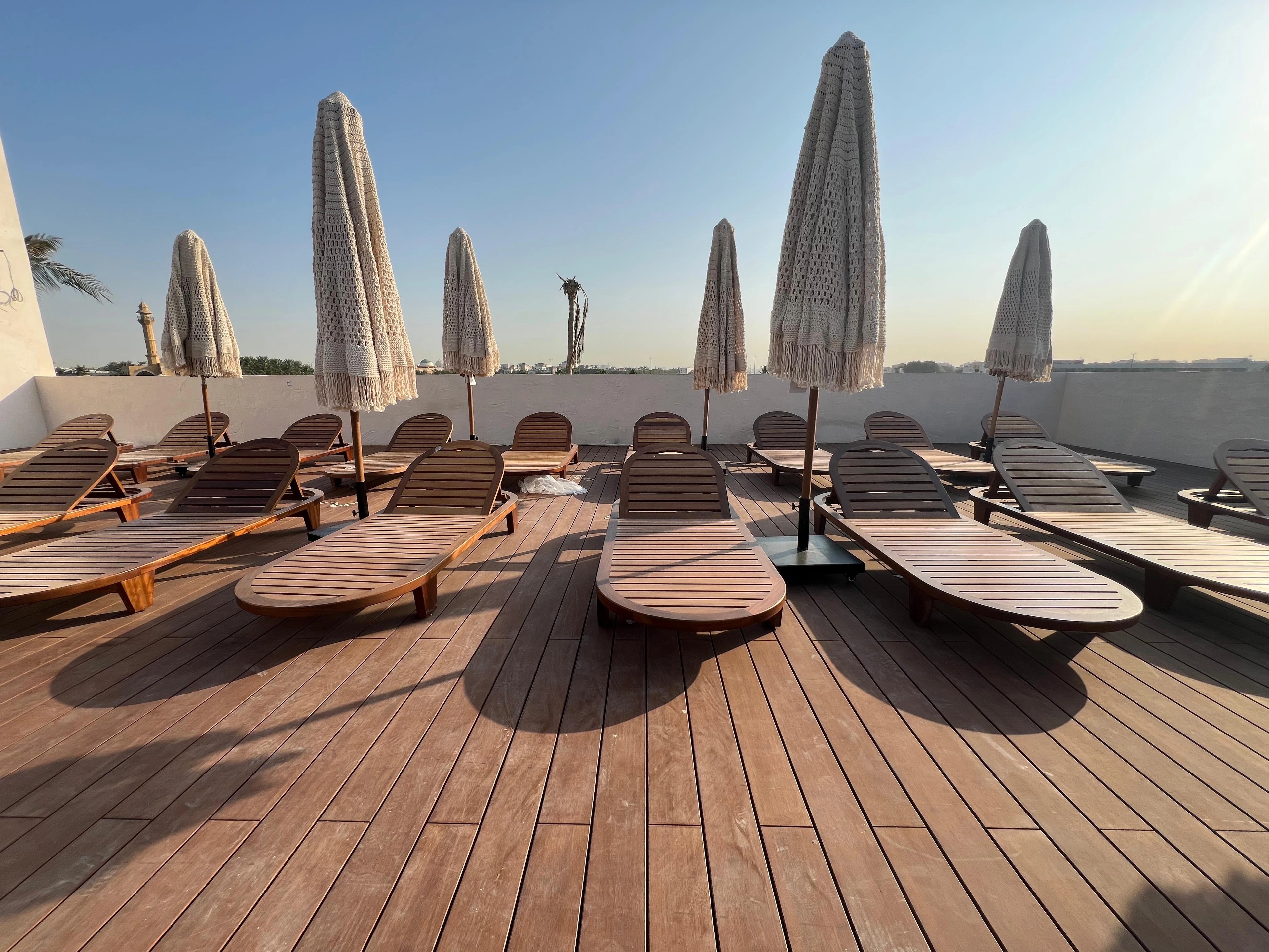 Warm timber decking beneath sun loungers on a waterfront terrace