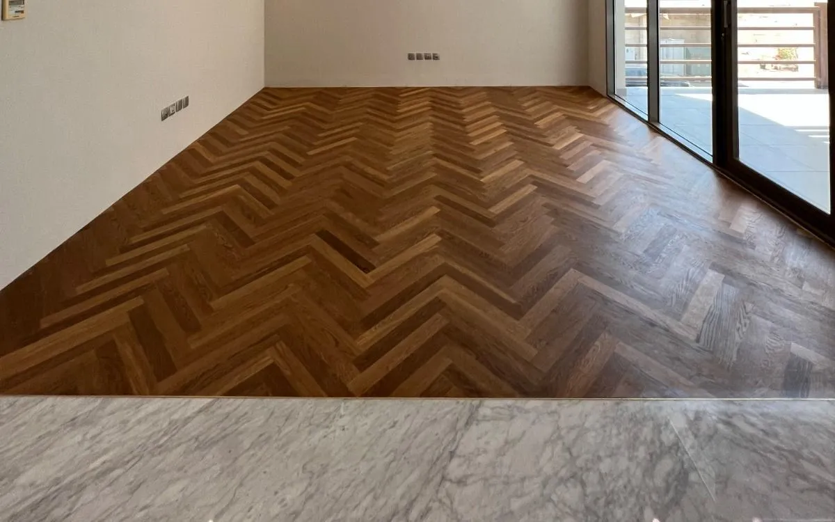 After — the finished chevron floor, cut to the marble threshold